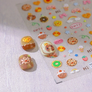 Colorful 3D dessert nail art stickers featuring cookies and donuts on a soft purple background