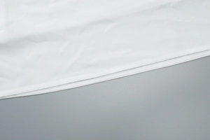 Gros plan sur la texture fine et les coutures de l'ourlet de la robe blanche en V