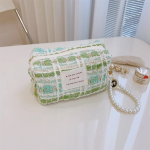 Close-up of green tweed handbag featuring pearl handle and chic black bow detail