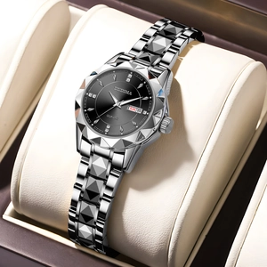 Close-up of silver watch with black dial, diamond markers, and day-date window on beige cushion