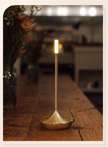 Close-up of golden brushed metal LED lantern lamp with ring handle on wooden table