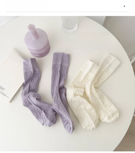 Detail of hollow knit texture and ribbed cuffs on purple and cream cotton socks