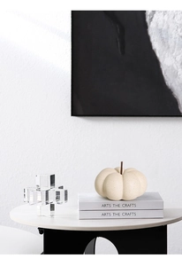 Minimalist ceramic pumpkin decor with black speckled texture on white marble table
