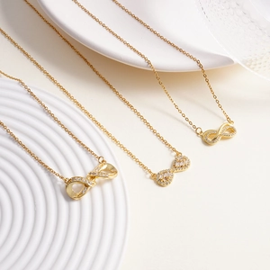 Three elegant gold infinity necklaces with sparkling cubic zirconia on a white pedestal