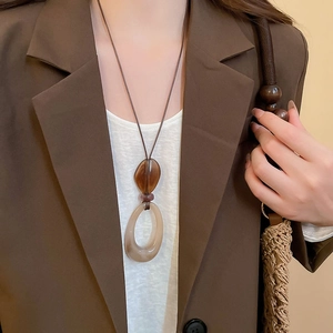 Detail of a vintage amber resin oval pendant necklace with a minimalist brown cord