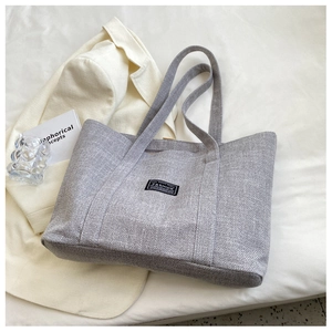 Detail of grey woven tote bag with fashion label on a minimalist aesthetic background