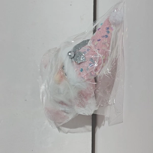 Detailed close-up of a pink plush Santa ornament with silver sequins in clear packaging
