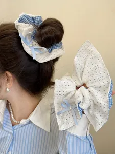 Detail of lace scrunchie with blue plaid trim, ribbon bow and pearl accent