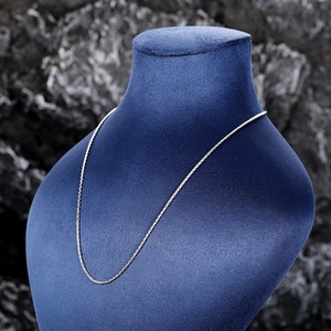 Detailed view of a sleek silver minimalist link chain on a blue velvet neck display