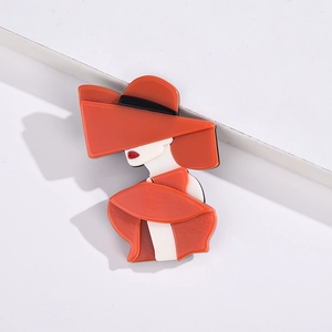 Detailed close-up of a stylish acrylic brooch featuring a lady in a chic red hat and coat