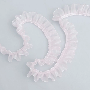 Macro detail of pink organza pleated lace trim showing wavy ruffle texture and material
