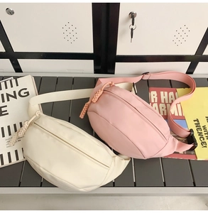 Detail showing cream and pink crescent waist bags with adjustable straps and zipper pulls