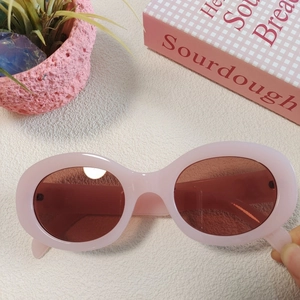 Detailed macro view of pink oval Y2K sunglasses with dark red lenses and retro aesthetic