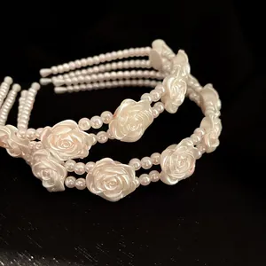 Detailed macro view of white resin roses and layered pearl beads on a vintage headband