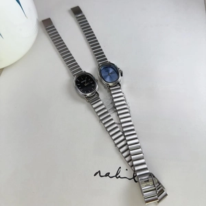 Close-up of elegant oval dial watches with silver alloy bands on a stylish magazine