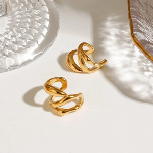 Detailansicht der goldene mehrlagige Spiral-Ohrklemmen auf minimalistischem Hintergrund