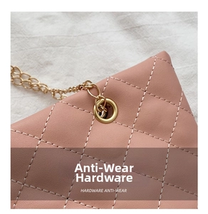 Primer plano de bolso rosa acolchado con cadena de oro fina y detalles metálicos de calidad