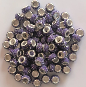 Macro shot of purple clay pave beads with crystals and metal eyelets for DIY jewelry
