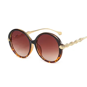 Fashionable oversized round sunglasses with brown gradient lenses and gold feather temples
