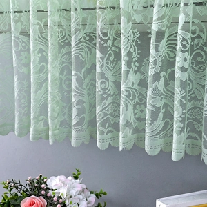 Close-up of light green lace cabinet curtain featuring floral patterns and scalloped edges