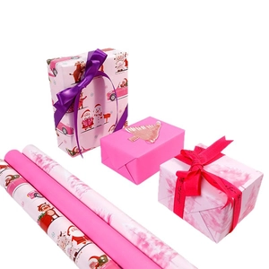 Pink Christmas wrapping paper rolls with Santa Claus patterns and festive ribbons