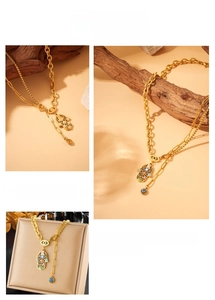 Detail of gold-plated Hamsa Hand and colorful Evil Eye charms on layered chain necklace