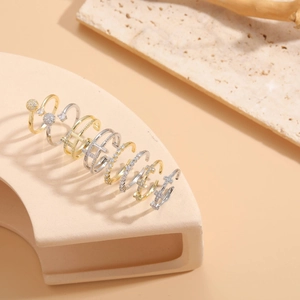 Macro detail of mixed metal rings featuring cross shapes and zircon stones on stone base