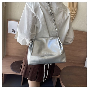 Detail of silver metallic tote bag featuring glossy PU texture and chain shoulder strap