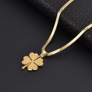 Flat gold snake chain necklace with hollow four-leaf clover pendant on a black texture