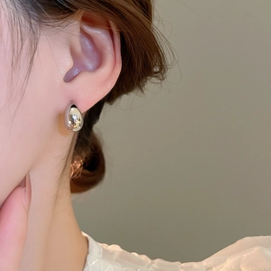 Close-up of minimalist silver water drop earring worn to show sleek metallic texture