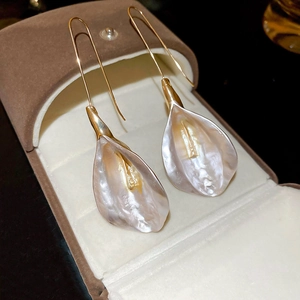 Détail macro des boucles d'oreilles calla avec crochets dorés sur velours brun