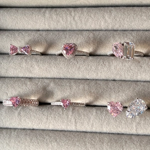 Détail de plusieurs bagues avec zircons roses en forme de cœur dans un écrin en velours