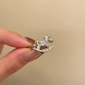 Detailed macro view of silver zircon rocking horse ring held to show scale and design