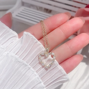 Close-up of heart-shaped gold necklace with baguette-cut zircons on a slender chain