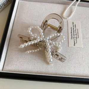 Detailed shot of brown resin hair claw clip with faux pearl bow and gold spring