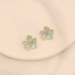 Boucles d'oreilles fleurs en émail bleu et bordure dorée sur un support épuré