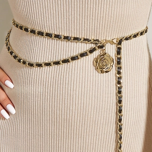 Détail de la ceinture chaîne dorée avec cuir noir et pendentif fleur de rose