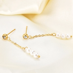 Detail of 18K gold-plated long chain earrings featuring white pearls and zircon stone