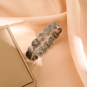Modern minimalist silver wave hollow bangle with textured geometric lines on silk