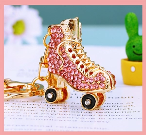 Close-up of a pink rhinestone roller skate keychain with gold metal details and white wheels