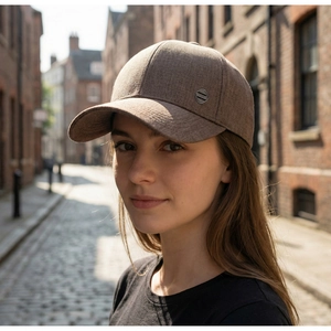 Détail d'une casquette de baseball en tissu marron foncé avec un emblème en métal argenté