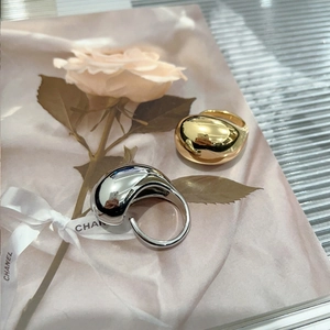 Detail of chunky teardrop gold and silver plated rings on a soft floral card