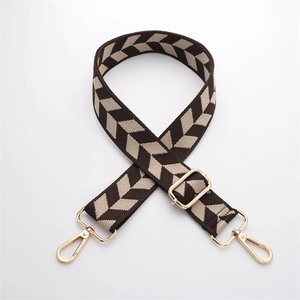 Close-up of adjustable woven arrow pattern bag strap with gold metal hooks and buckles