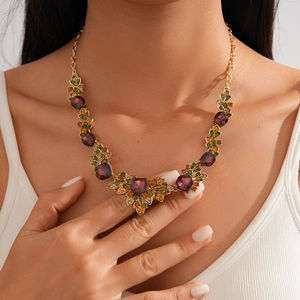 Detailed view of vintage gold necklace featuring a purple square stone and floral crystals