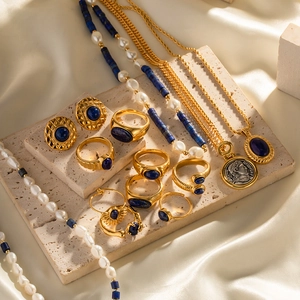 Lapis lazuli and gold jewelry set displayed on silk with vintage coin pendant