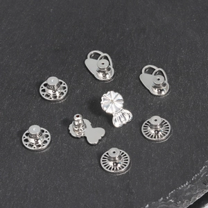 Macro shot of assorted silver metal earring back lifters on a dark stone background