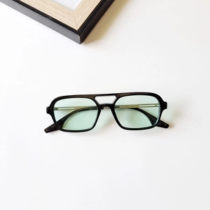 Détail de lunettes de soleil rétro à double pont avec monture noire et verres verts