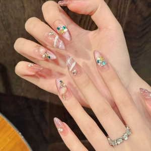 Macro detail of pink cat-eye press-on nails with pearl, shell, and star decorations