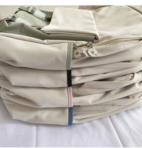 Detail of canvas backpack featuring daisy zipper pulls and multi-color piping design
