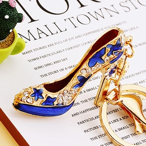 Macro detail of high heel keychain with blue enamel and rhinestones on decorative paper